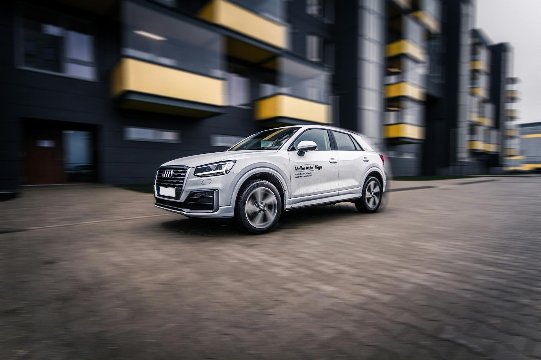 Nowoczesne Audi SUV jedzie szybko przez miasto wieczorem