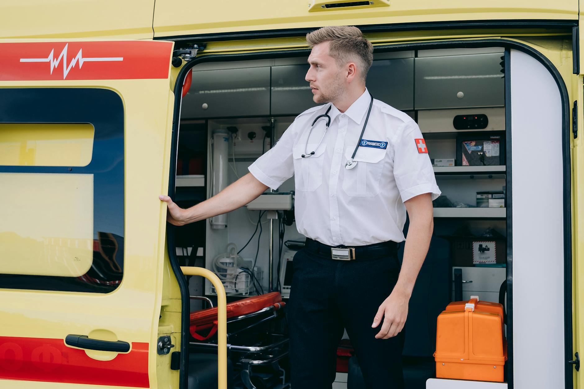 Ratownik medyczny stoi przy karetce z torbą ratunkową