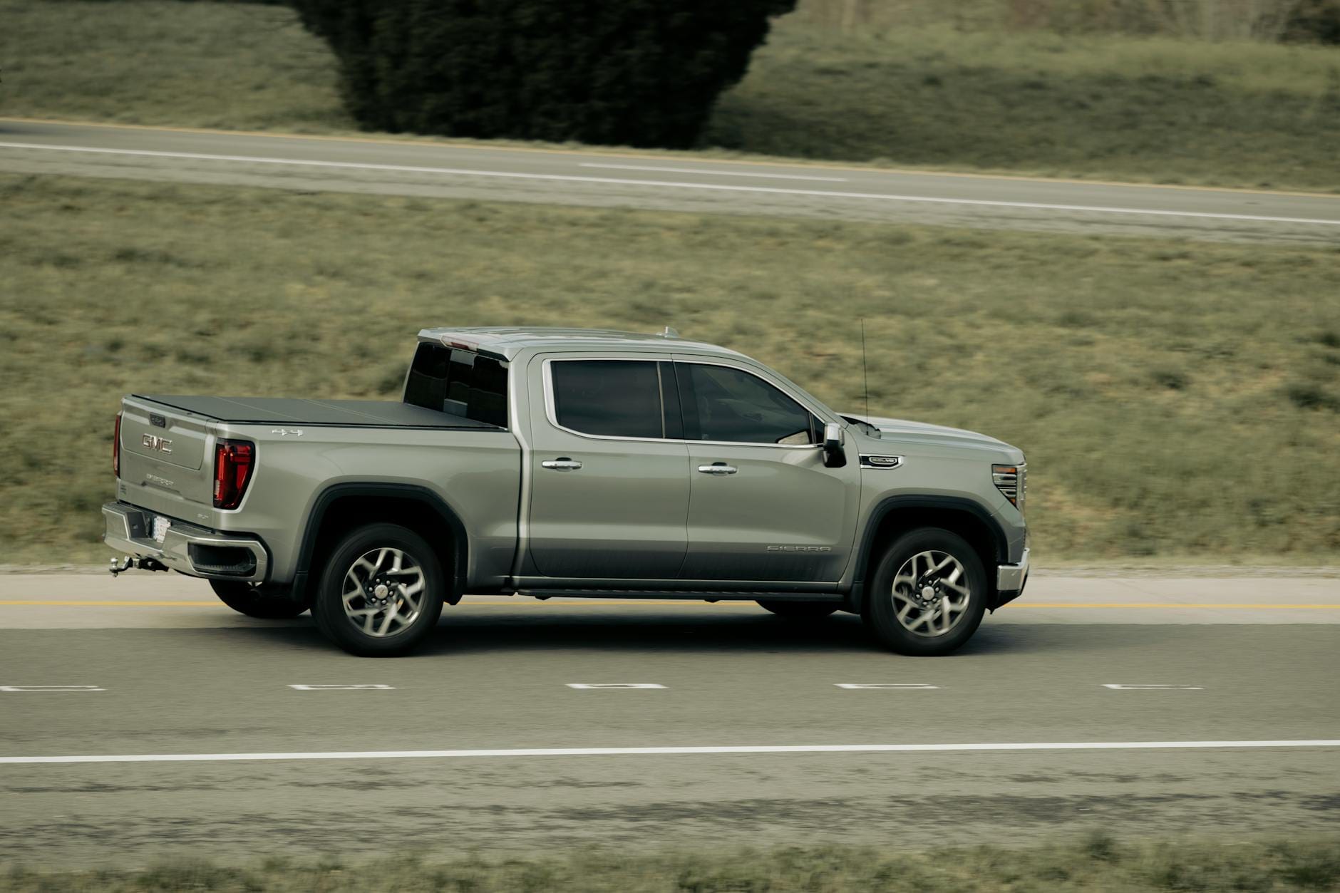 Jak ograniczyć spalanie w Oplu na autostradzie bez utraty komfortu jazdy Srebrny pickup jedzie autostradą na tle górskiego krajobrazu