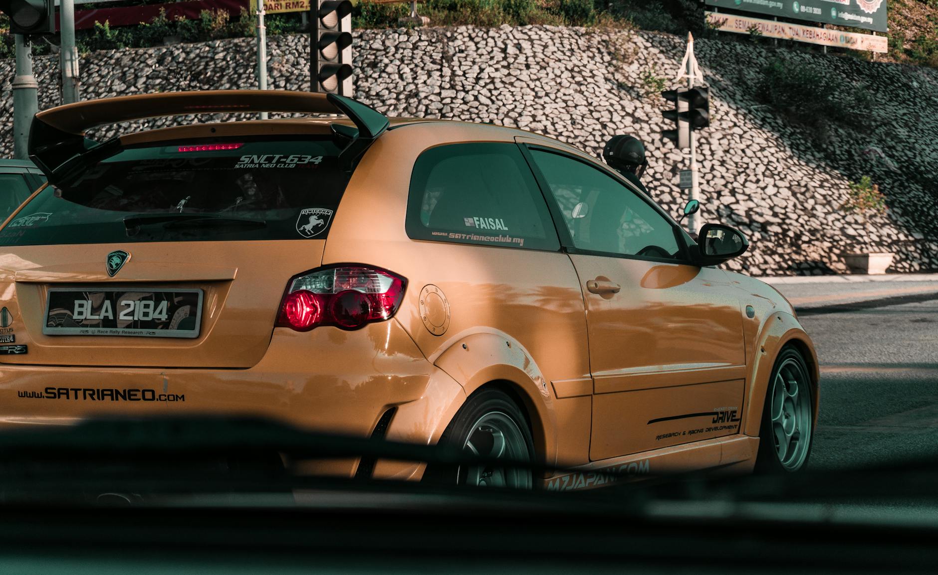 Żółty sportowy hatchback z modyfikacjami na skrzyżowaniu w mieście