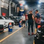 Zwiedzający oglądają sportowe auta w hali wystawowej