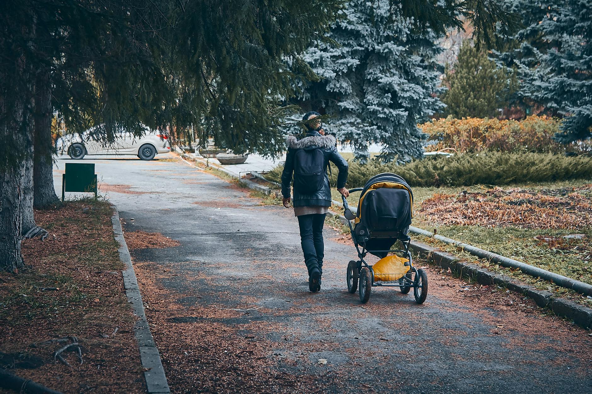Osoba spaceruje z wózkiem po parku jesienią