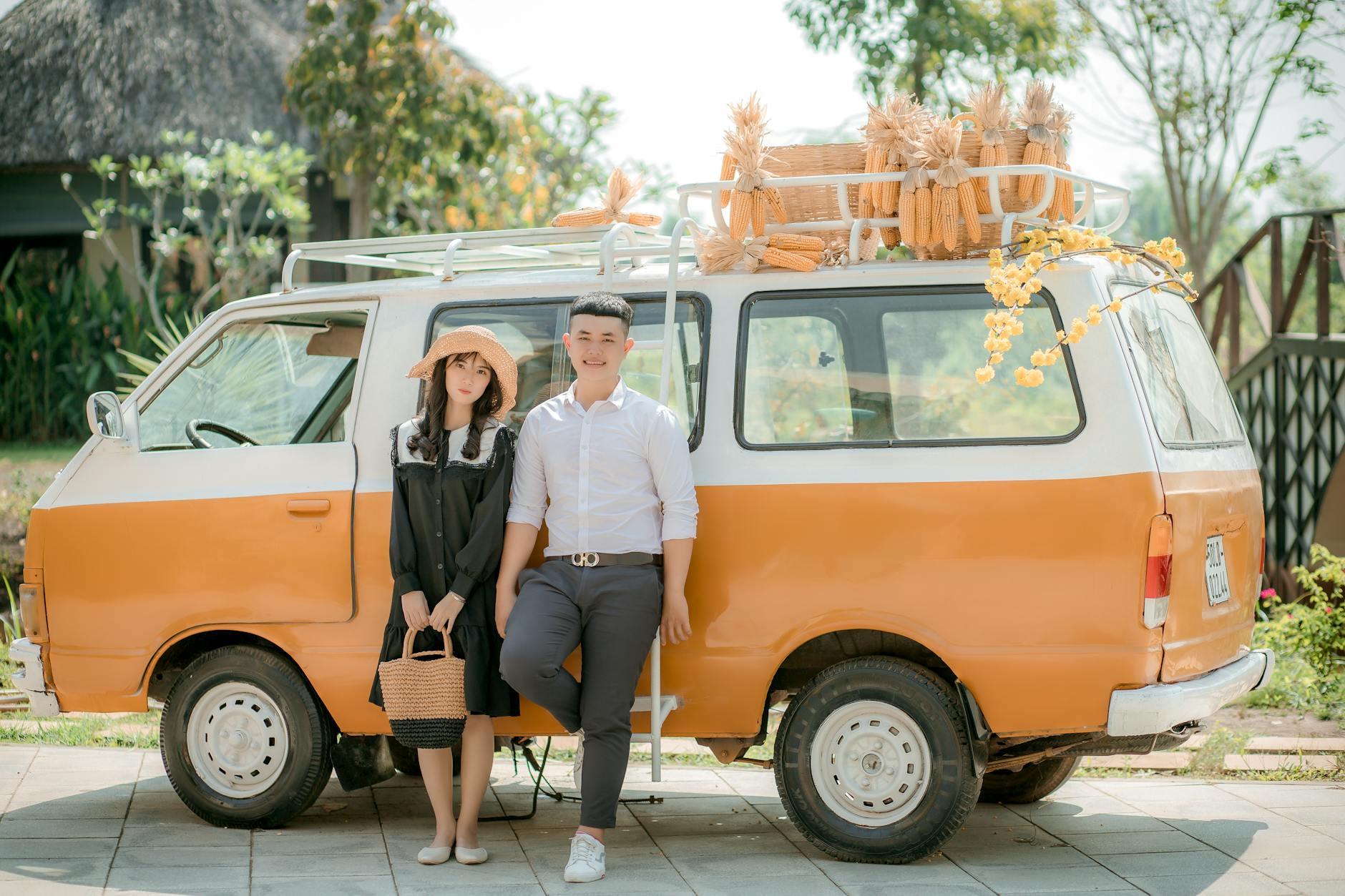 Uśmiechnięta para przy pomarańczowym zabytkowym vanie pełnym kukurydzy