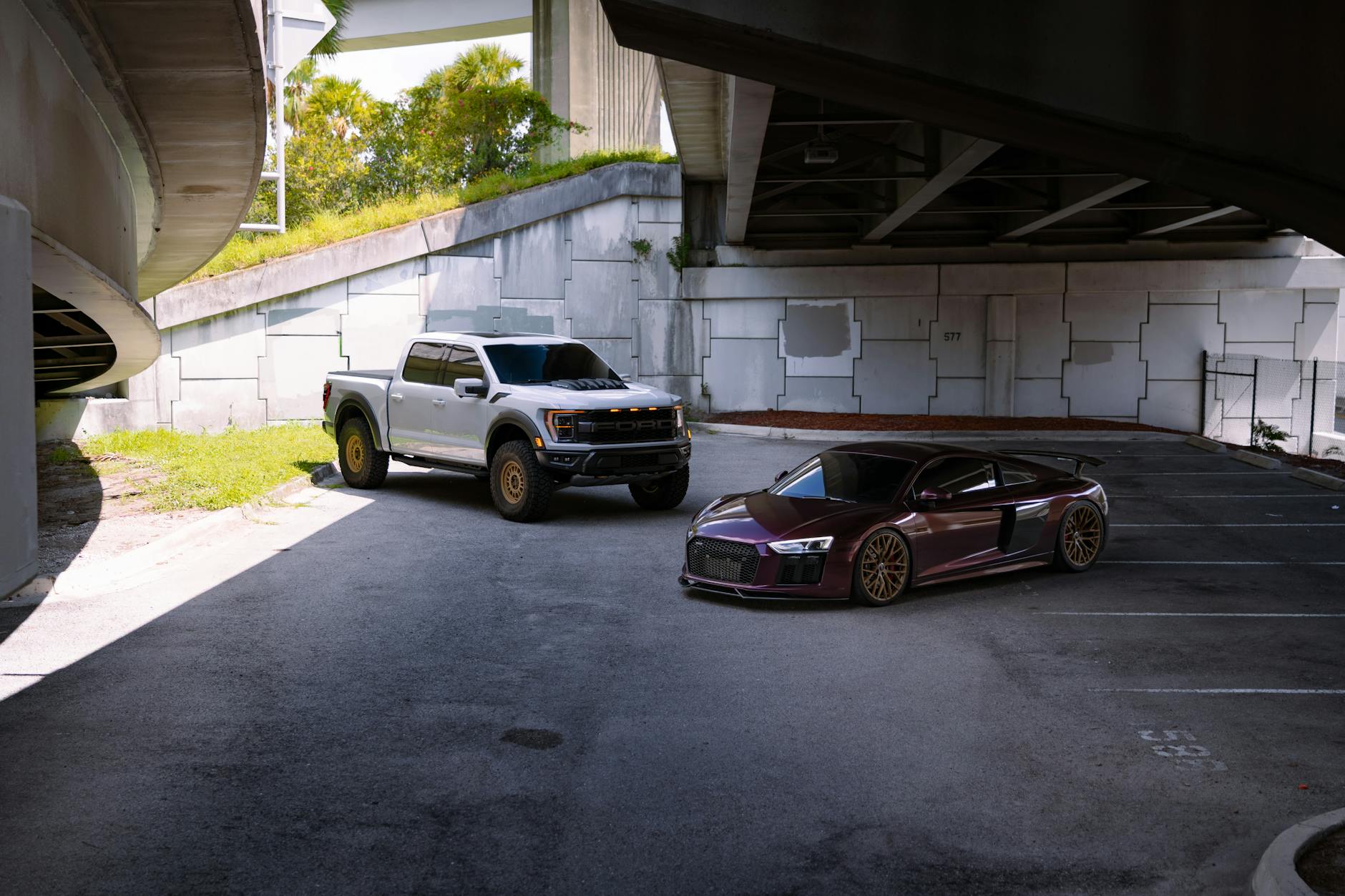 Srebrny pickup i czerwone auto sportowe pod wiaduktem w mieście