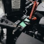 Jak bezpiecznie odpalić Opla z kabli: kolejność, ryzyka dla elektroniki i typowe błędy kierowców Akumulator Opla pod maską podłączony kablami rozruchowymi