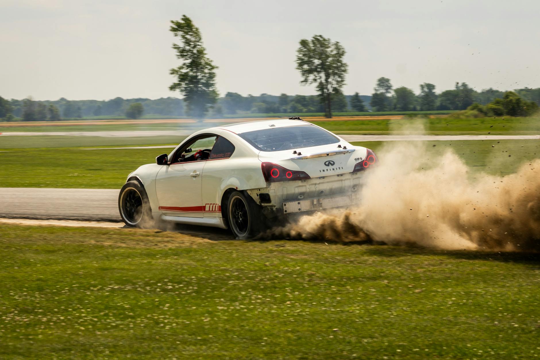 Biały Opel sportowy w kontrolowanym poślizgu na torze wyścigowym
