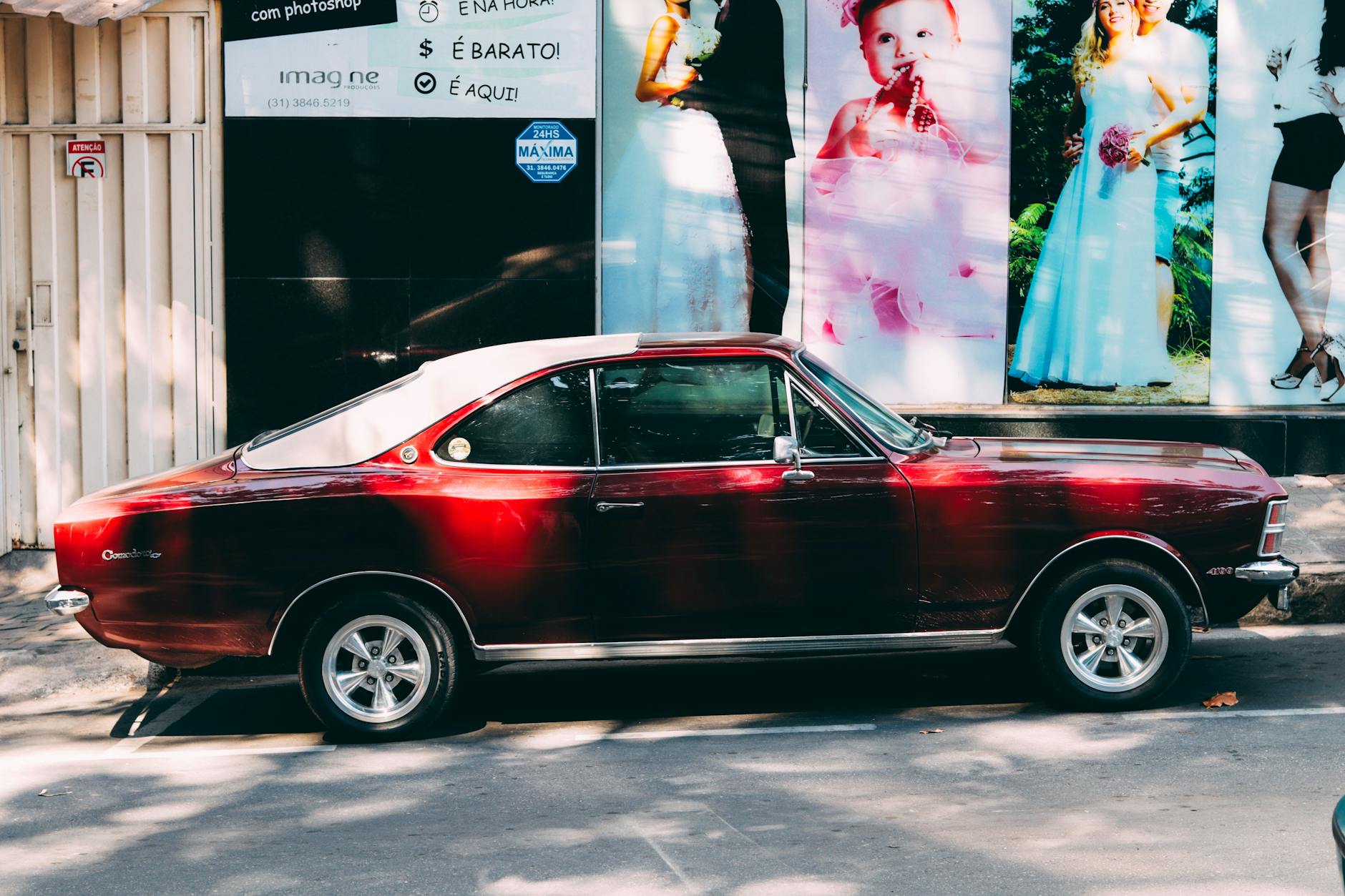 Czerwony zabytkowy samochód na ulicy z plakatami reklamowymi