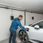 Opel elektryk w bloku: jak ładować bez własnego gniazdka i co mówi prawo wspólnot mieszkaniowych? Mężczyzna podłącza elektrycznego Opla do ładowarki w garażu podziemnym